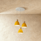 Closer view of the Clérachic three-head yellow wood disc pendant light cluster on its round ceiling canopy.