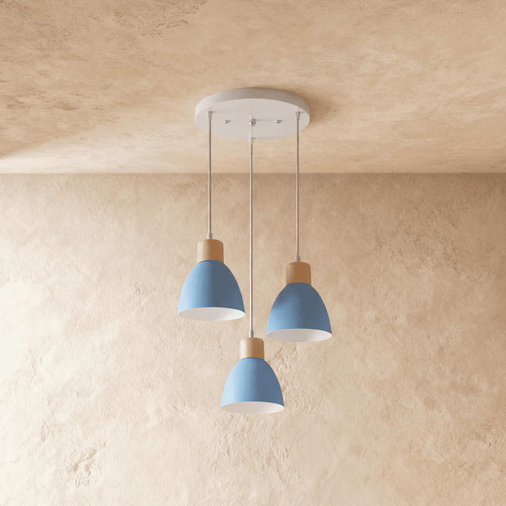 Three Clérachic wood disc pendant lights in dusty blue cluster from a round canopy over a warm plaster backdrop.