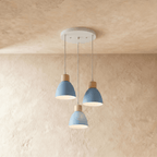 Angled view of the Clérachic three-head blue wood disc pendant light cluster hanging from its round canopy.