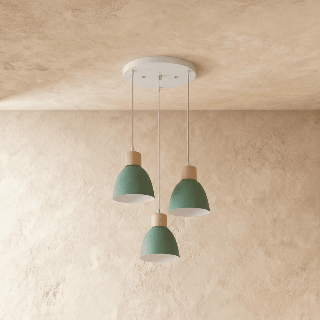 Three Clérachic wood disc pendant lights in sage green cluster from a round canopy against a plaster wall.