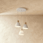 Angled view of the Clérachic three-head white wood disc pendant light cluster hanging from its round canopy.