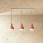 Closer view of the Clérachic three-head pink wood disc pendant light row on its slim linear ceiling bar.