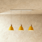 Angled view of the Clérachic three-head yellow wood disc pendant light row hanging from its linear ceiling bar.