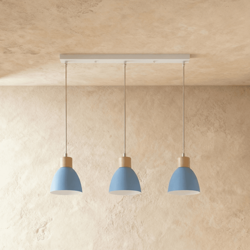 Three Clérachic wood disc pendant lights in dusty blue hang in a row from a linear bar for a kitchen island.