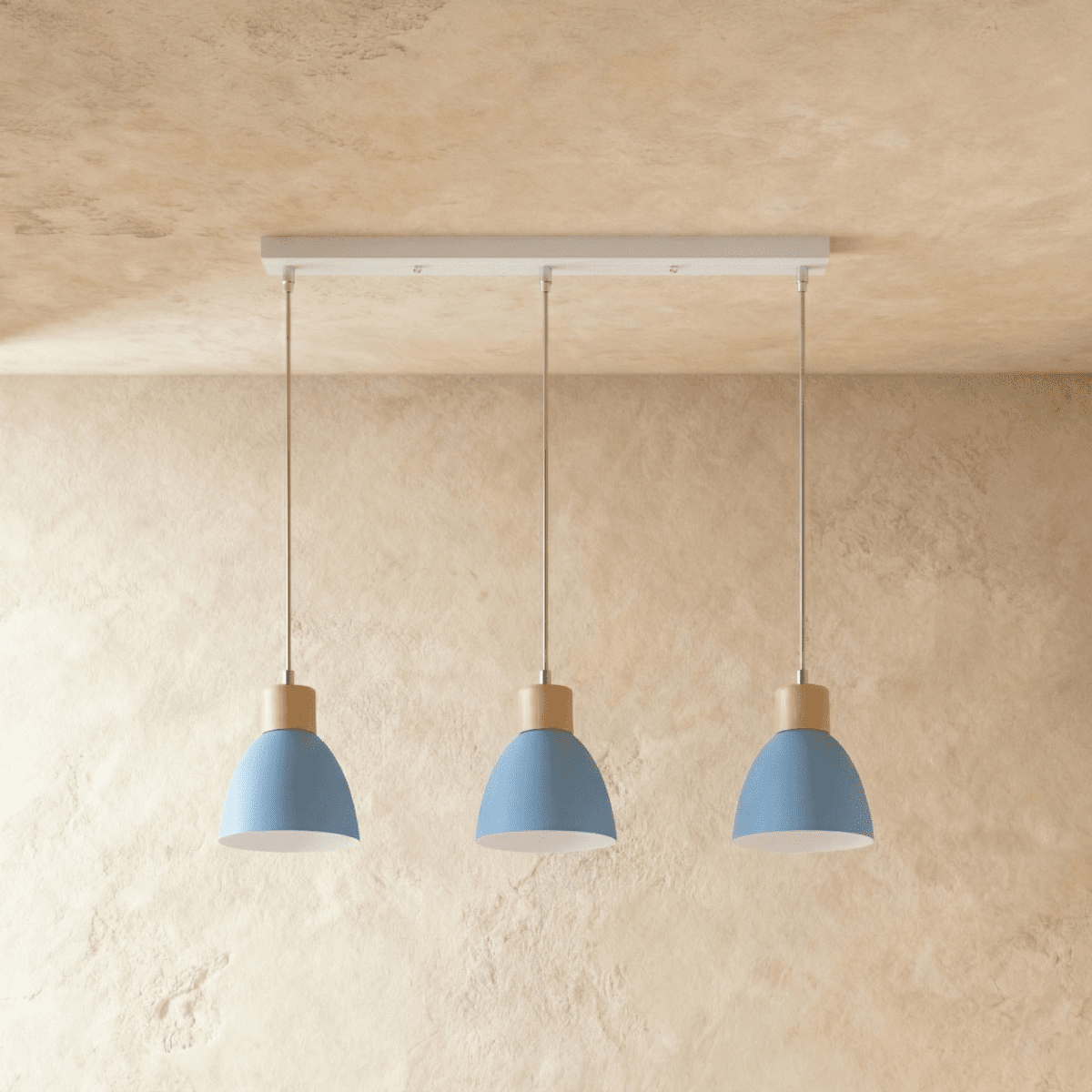 Three Clérachic wood disc pendant lights in dusty blue hang in a row from a linear bar for a kitchen island.