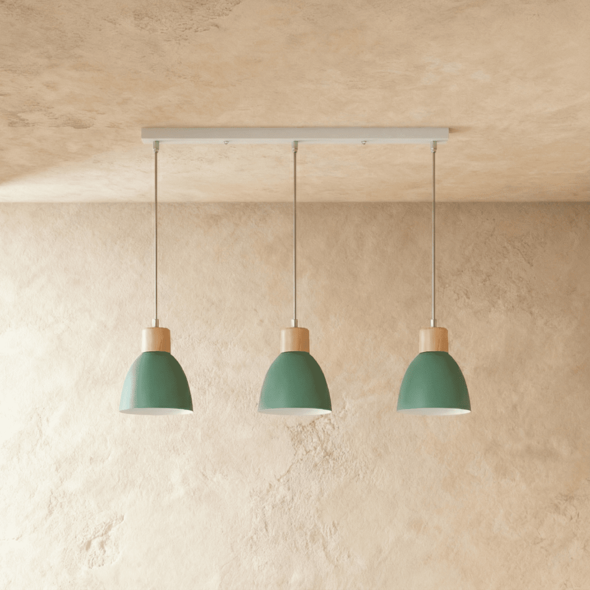 Three Clérachic wood disc pendant lights in sage green hang in a row from a linear bar over a plaster wall.