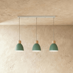 Angled view of the Clérachic three-head green wood disc pendant light row hanging from its linear ceiling bar.