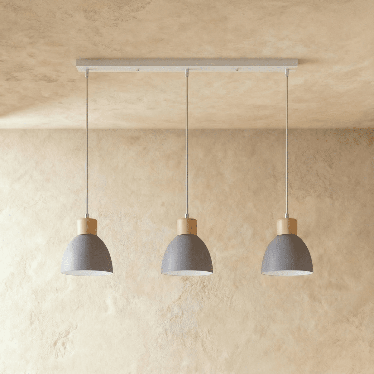 Three Clérachic wood disc pendant lights in matte grey hang in a row from a linear bar for a kitchen island.