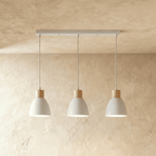 Angled view of the Clérachic three-head white wood disc pendant light row hanging from its linear ceiling bar.