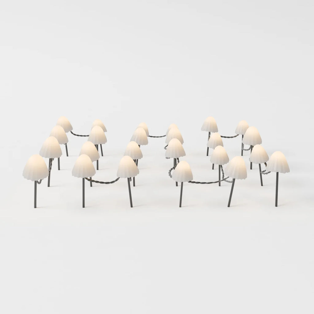 Clérachic solar mushroom stake lights, a cluster of cream glass mushroom caps on dark stems, linked by a woven cord, glowing warm white.