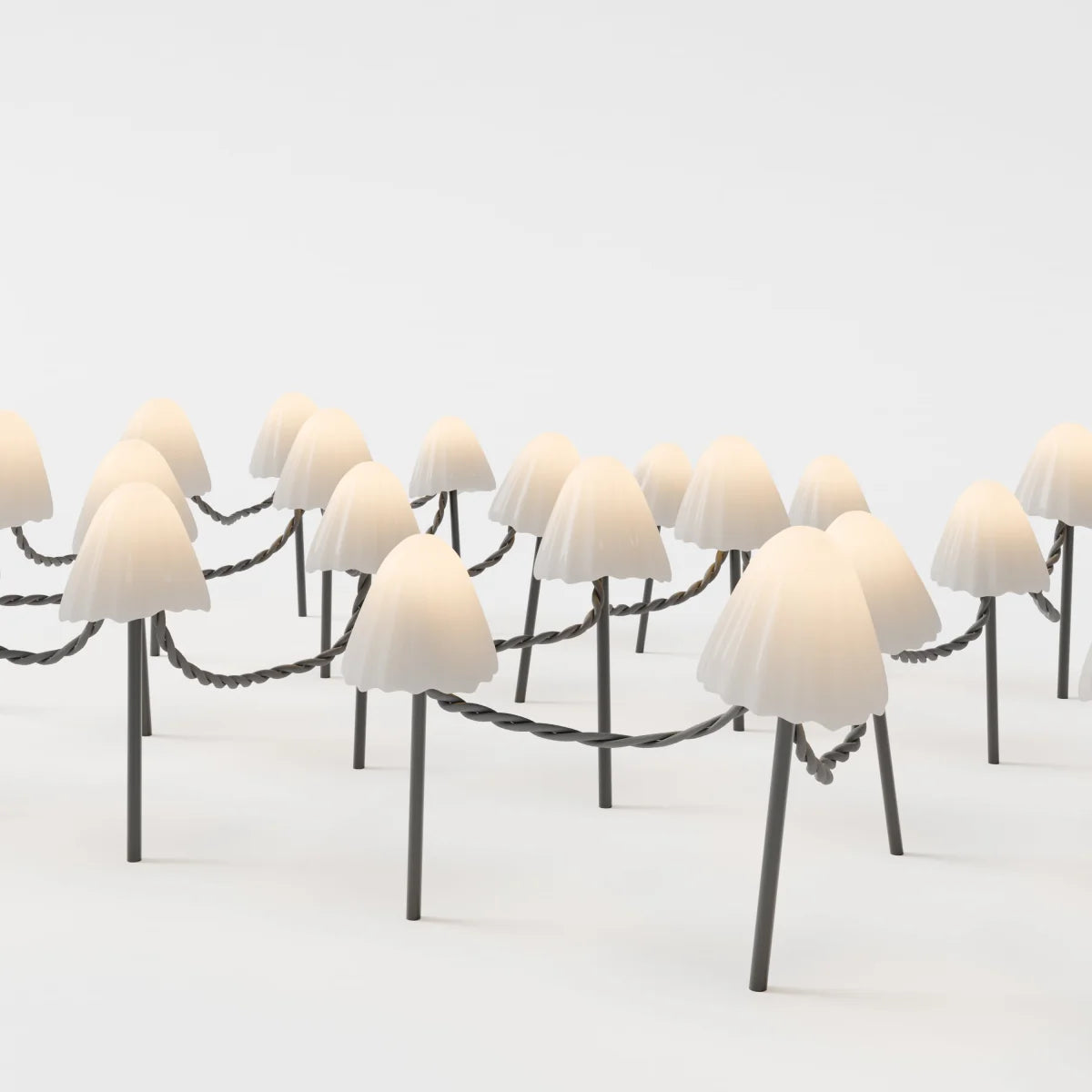 Close angle on Clérachic solar mushroom stake lights, ribbed cream glass caps glowing warm white above slim dark metal stems.