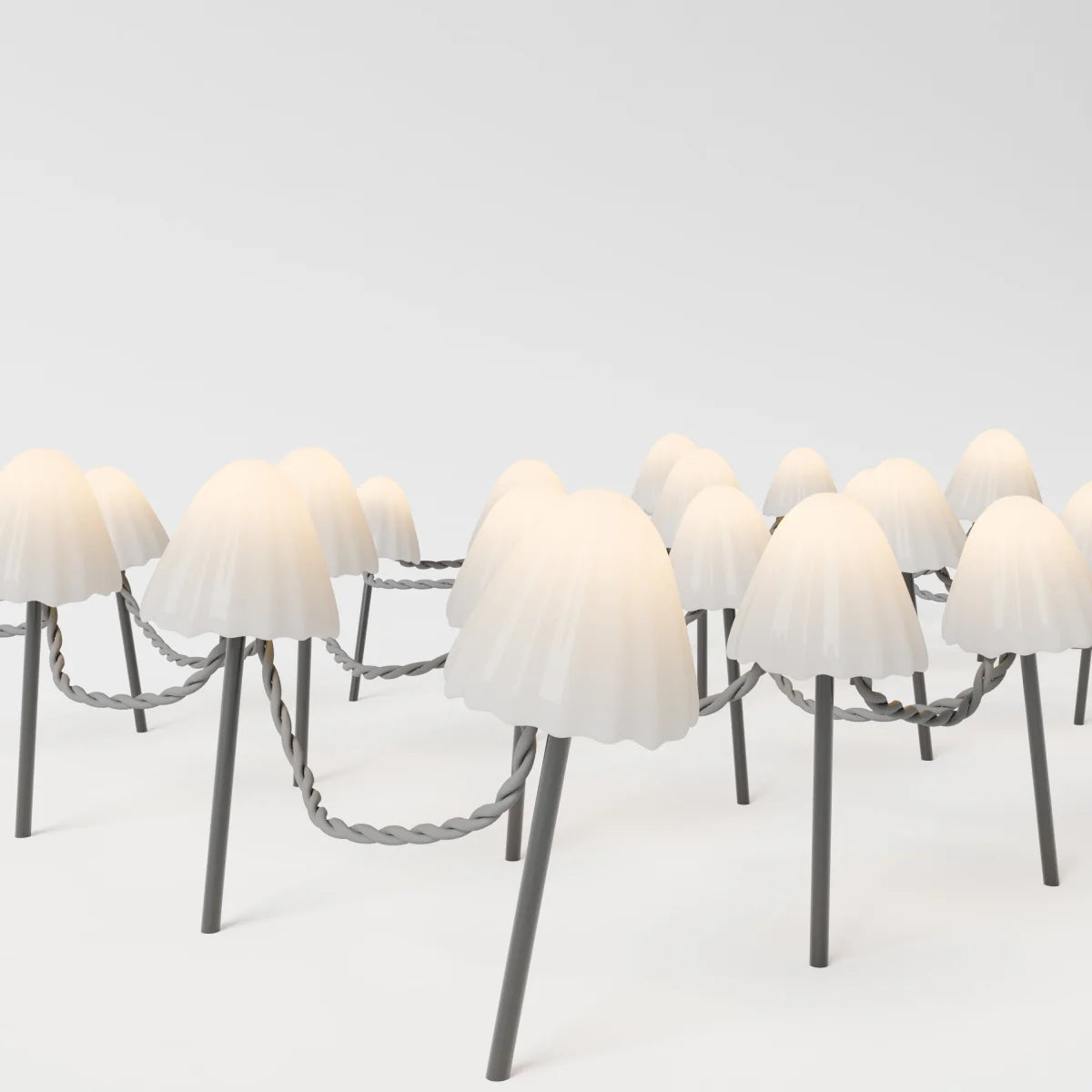 Macro detail of Clérachic solar mushroom stake lights, the ruffled cream glass caps glowing warm white against a plain backdrop.