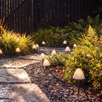 Sunlit view of Clérachic solar mushroom stake lights beside a gravel path, warm white glow visible under golden foliage.