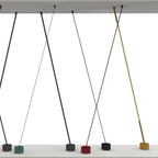 Render of Clérachic floor lamp strips of different widths crossing between a ceiling panel and bases in green, black, red and gold.