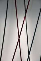 Close view of black and red Clérachic floor lamp strips crossing, in front of a softly lit grey wall.