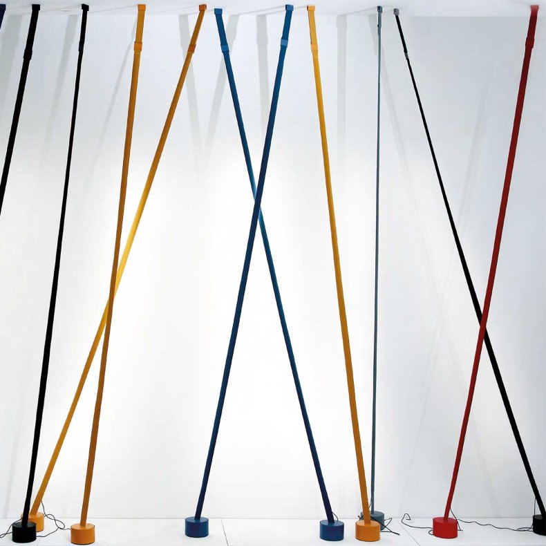 A row of black, ochre, blue, grey and red Clérachic floor lamp strips lean in front of a softly lit white wall.
