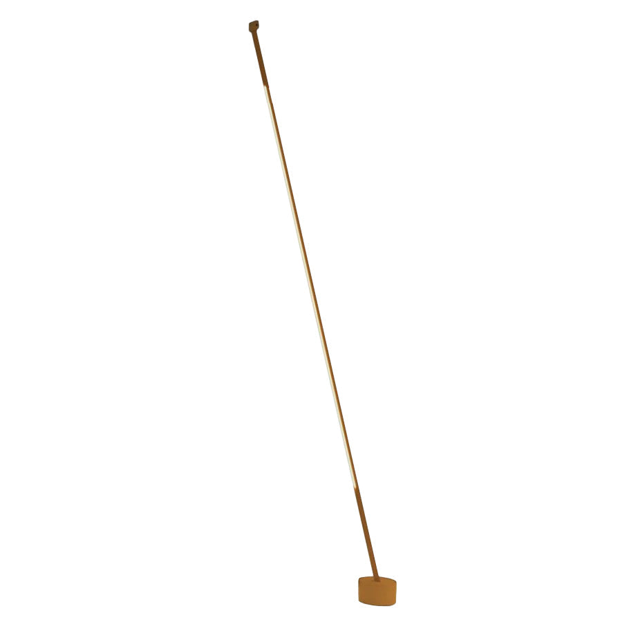 A lit ochre Clérachic floor lamp strip leans steeply to a round ochre base on a plain white backdrop.