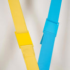 Close view of a yellow and a light blue Clérachic floor lamp strip, each with a metal joining sleeve over the woven webbing.