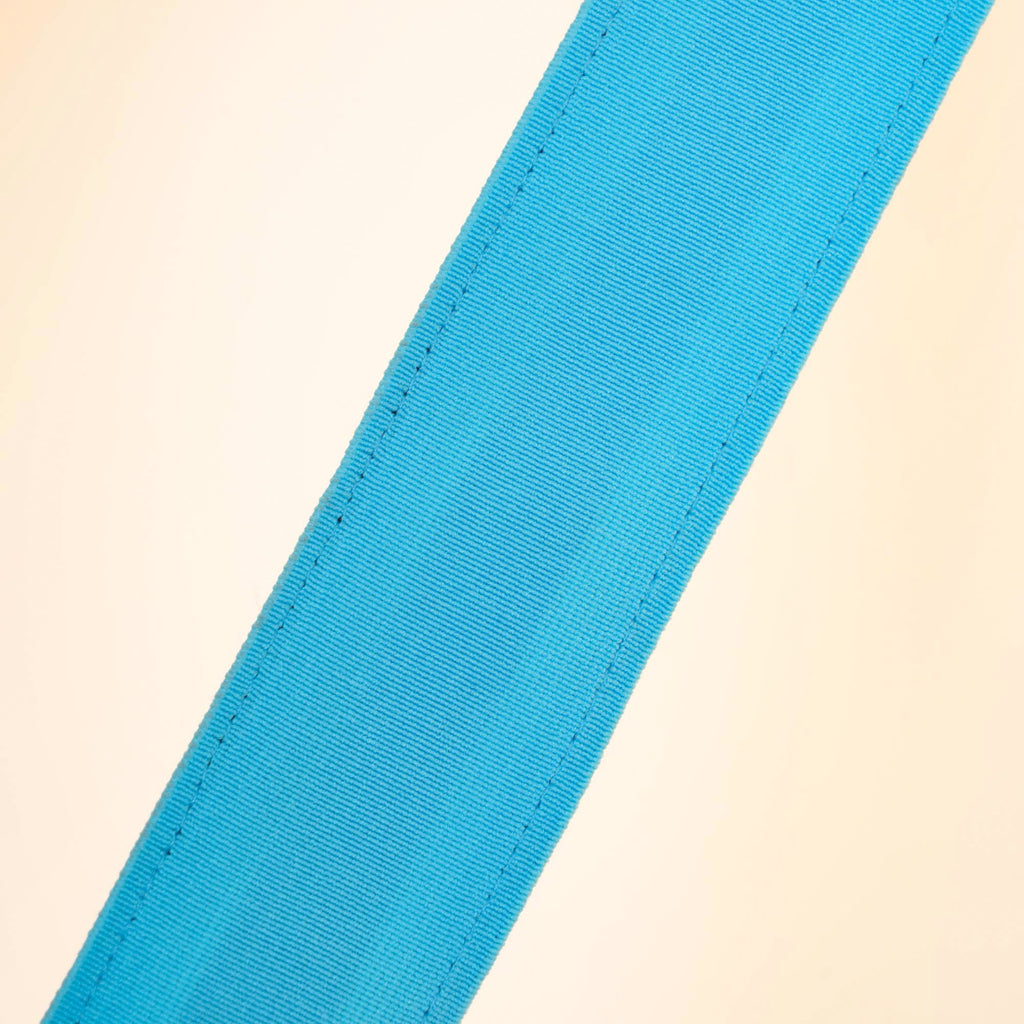 Close view of a light blue webbing strip of a Clérachic floor lamp, showing its fine ribbed weave and stitching on a cream backdrop.