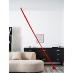 An unlit red Clérachic floor lamp strip leans from the ceiling to a red base, past a black sideboard and a framed line drawing.
