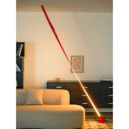 The lit lower part of this red Clérachic floor lamp glows bright and warm beside a beige sofa, with a black sideboard behind.