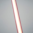 Close view of the lit lower length of this Clérachic floor lamp, the light glowing white inside red edges against a grey backdrop.