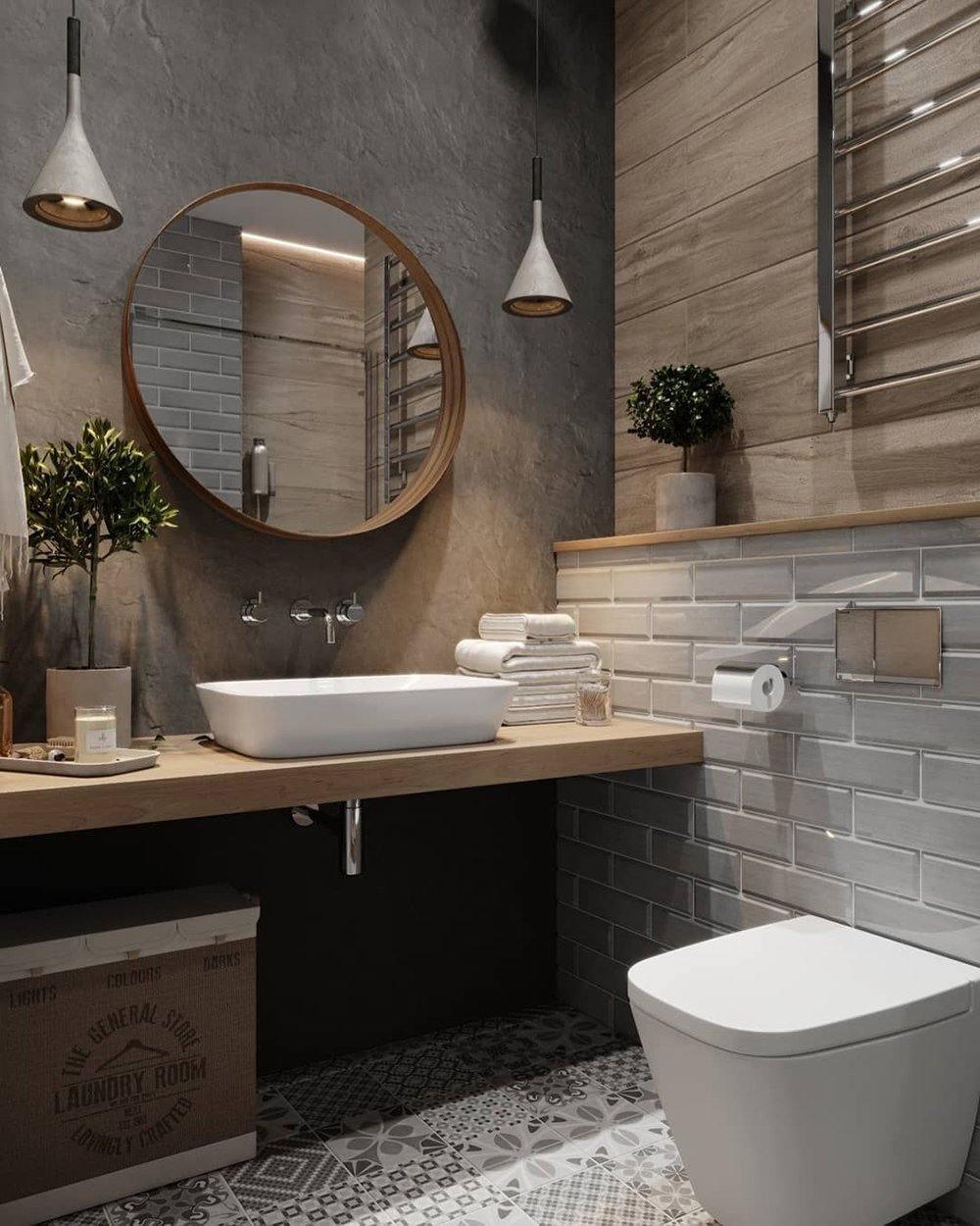 Two Clérachic cone pendants in a bathroom, with a round wood-framed mirror, a stone basin and grey tiles.