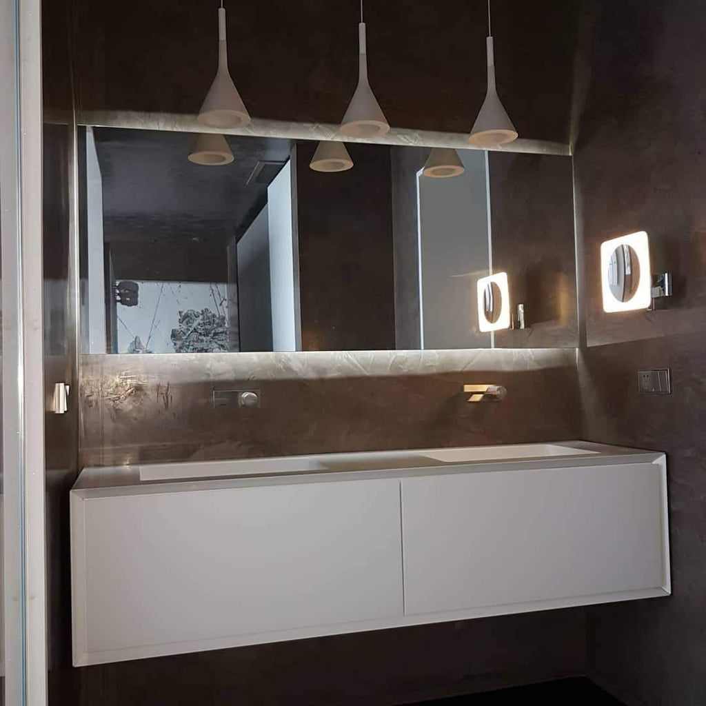 Three Clérachic cone pendants hung in a row above a mirror and a floating white vanity in a dark brown bathroom.