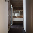 Three Clérachic cone pendants hung in a row over a mirror and white wall-hung vanity in a dark corridor bathroom.