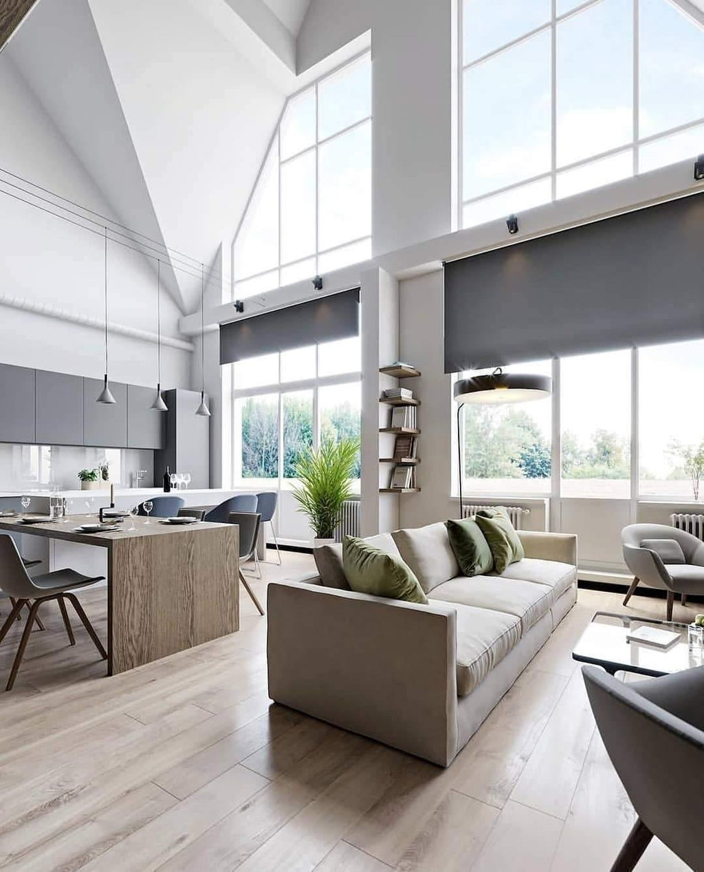 Slim grey Clérachic cone pendants hanging in a tall, bright open-plan room with big windows, a sofa and a long kitchen counter.