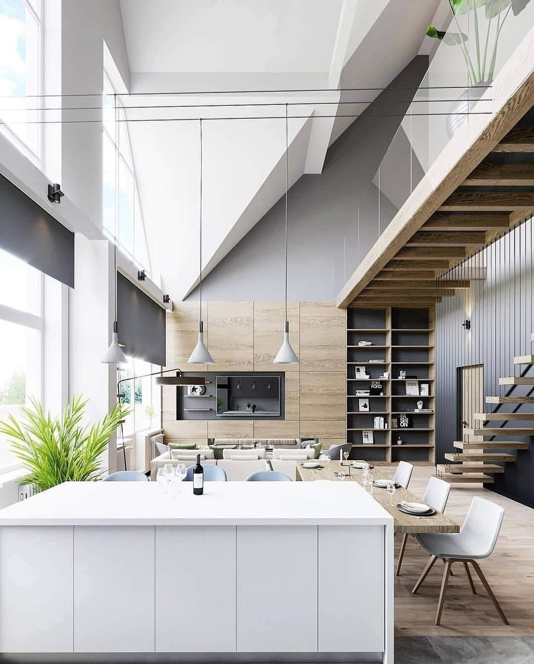 Clérachic cone pendants hung low in a double-height room, above a white island and dining table, with a timber staircase behind.