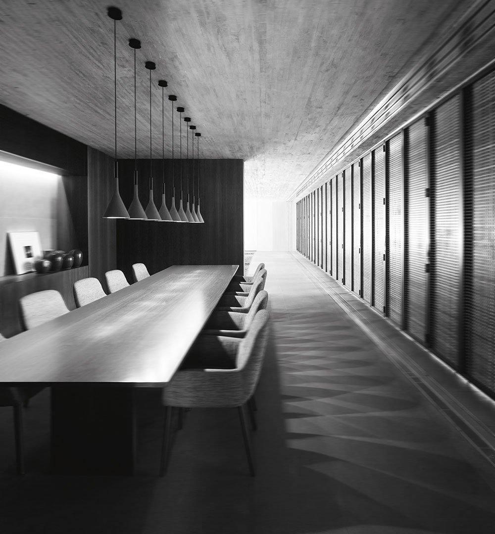 A long row of Clérachic cone pendants above a very long table in a black-and-white room with grey chairs and a bare concrete ceiling.