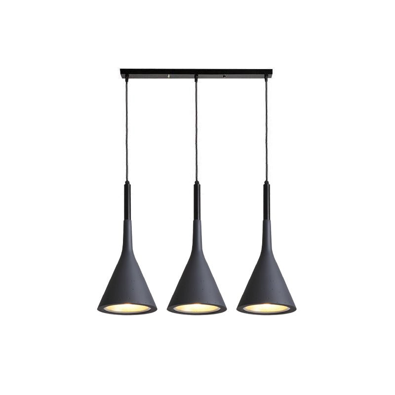 Three black Clérachic cone pendants hung from a long black bar, each with a gold-toned inner shade, on a white backdrop.