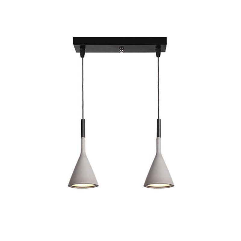 Two concrete grey Clérachic cone pendants hung from a short black bar, with a glimpse of the inner shade under each cone.
