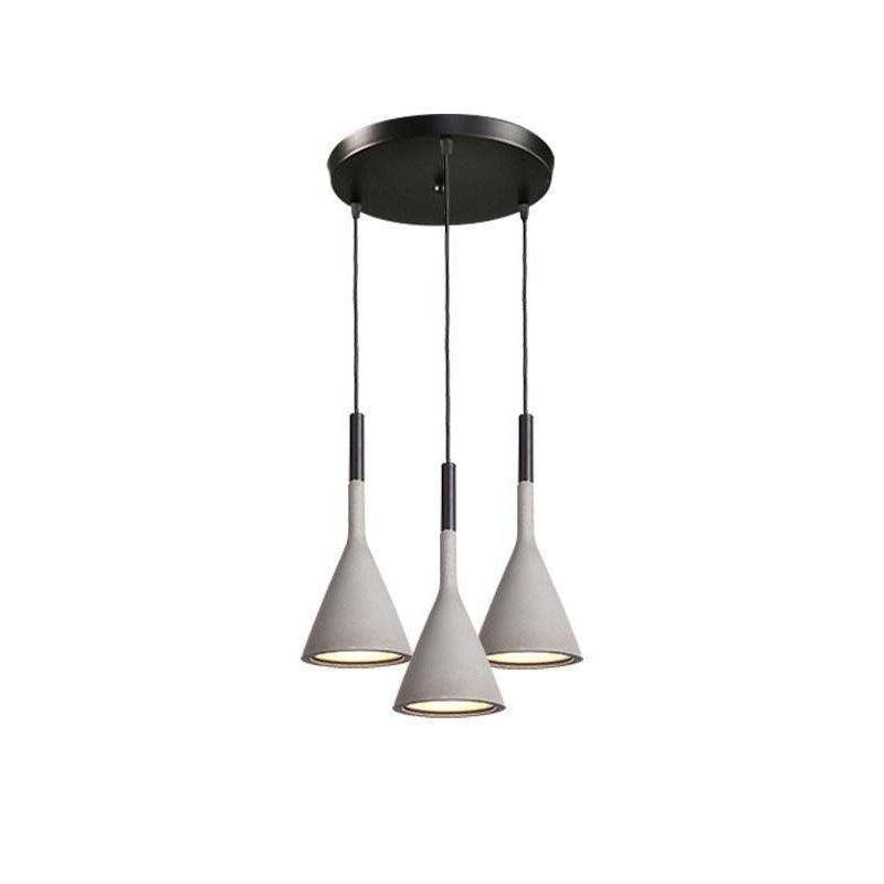 Three concrete grey Clérachic cone pendants hung from a round black canopy at different heights, on a white backdrop.