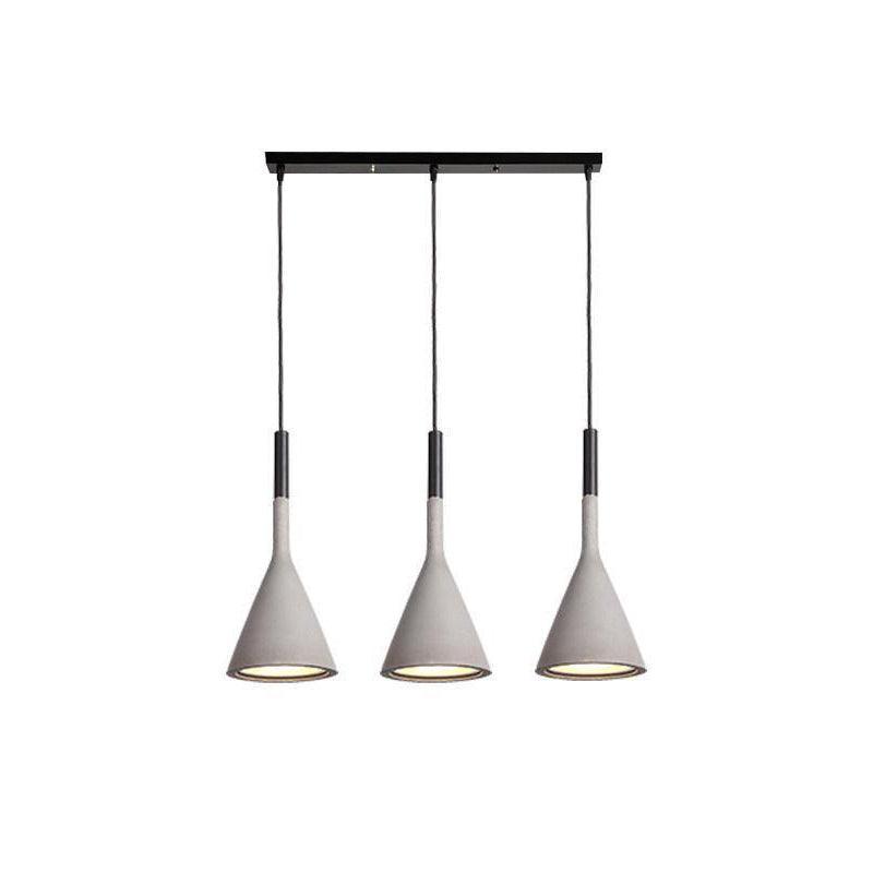 Three concrete grey Clérachic cone pendants hung in a line from a long black bar, with a gold-toned inner shade in each.