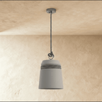 Clérachic grey concrete bucket pendant with a black-and-white braided cord wrapped around its shoulder, against warm plaster.