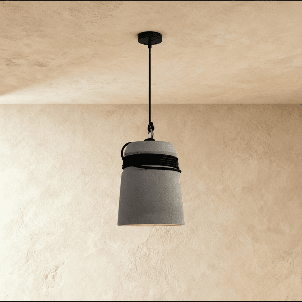 Clérachic grey concrete bucket pendant with black cord wound around its top, hung from a black rod and canopy on plaster.