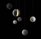 Six Clérachic concrete spheres float at different heights on a black backdrop, some glowing warmly through a slot or from the base.
