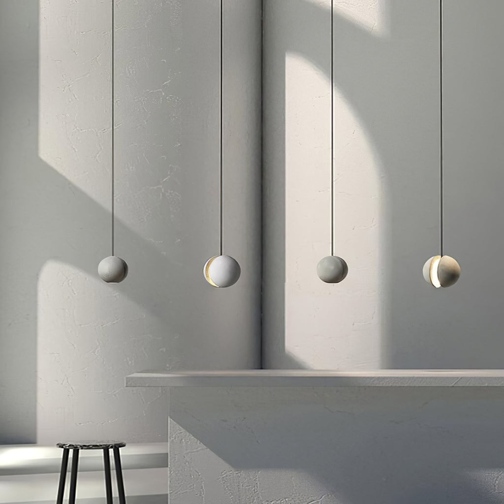 Four Clérachic spheres hang in a line before a rounded grey wall, with a stool and a pale counter in the lower corner.
