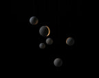 Seven Clérachic concrete spheres of different sizes float in a black space, a few of them glowing through a slot.