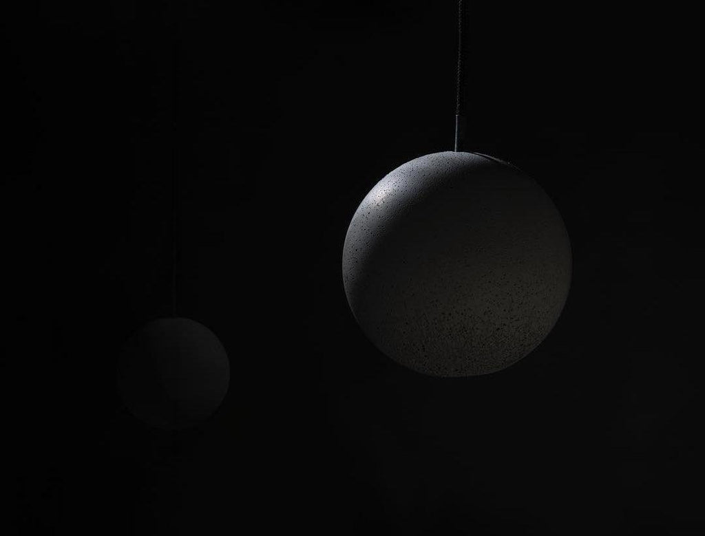 Close view of the rough, speckled concrete surface of a Clérachic sphere, with a second sphere blurred behind it.