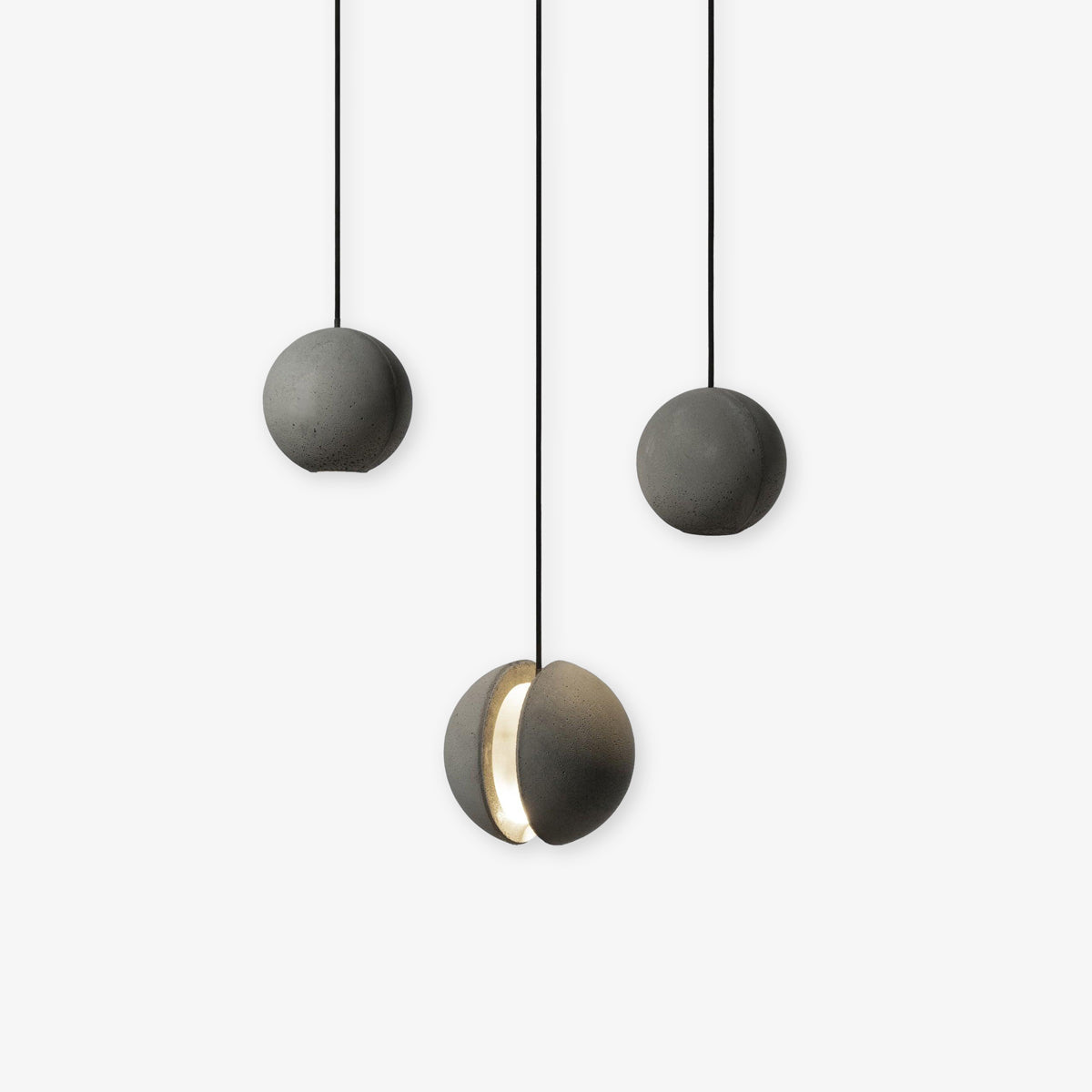 Three Clérachic pendants hang close together on a white backdrop, the lowest with its slot glowing warm.