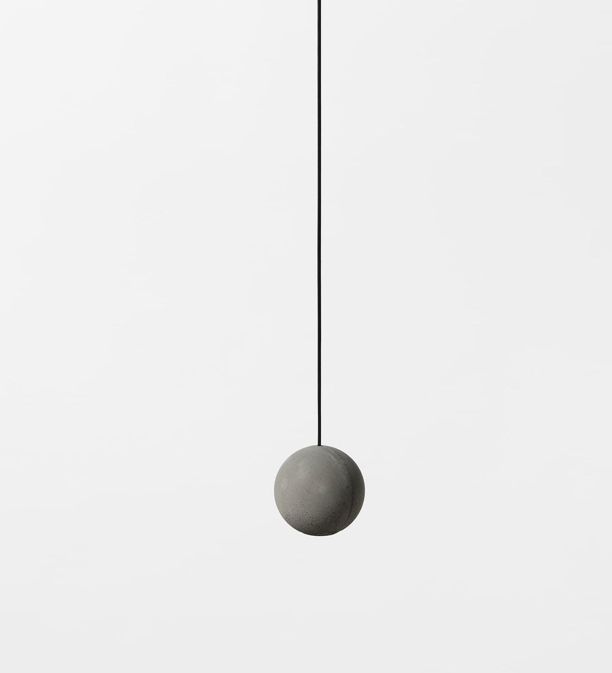 A single plain cement-grey Clérachic sphere hangs on a thin black cord against a pale backdrop.
