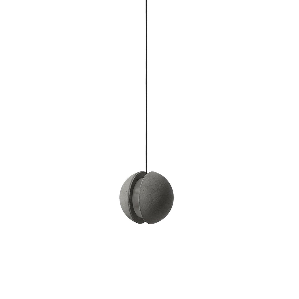 A slotted Clérachic concrete pendant, switched off, hangs on a black cord with the slit facing the side.