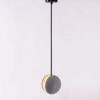 A Clérachic pendant shown straight on from a black canopy, a warm crescent of light along one edge.