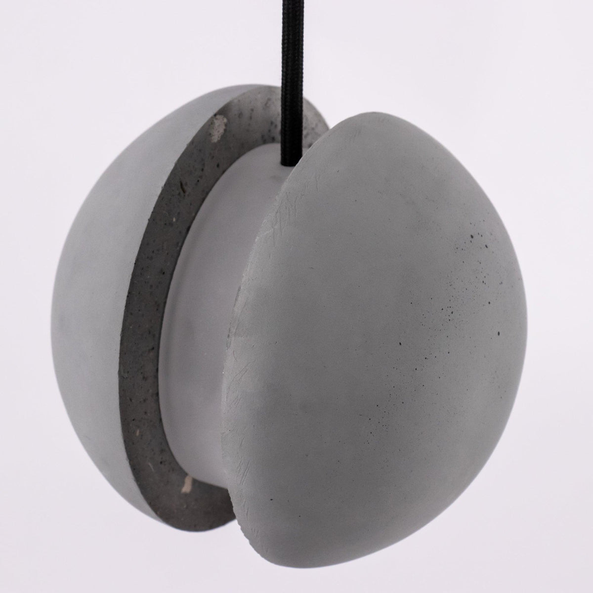 Close view of the two cement halves and the central core of this Clérachic pendant, with the cord entering at the top.