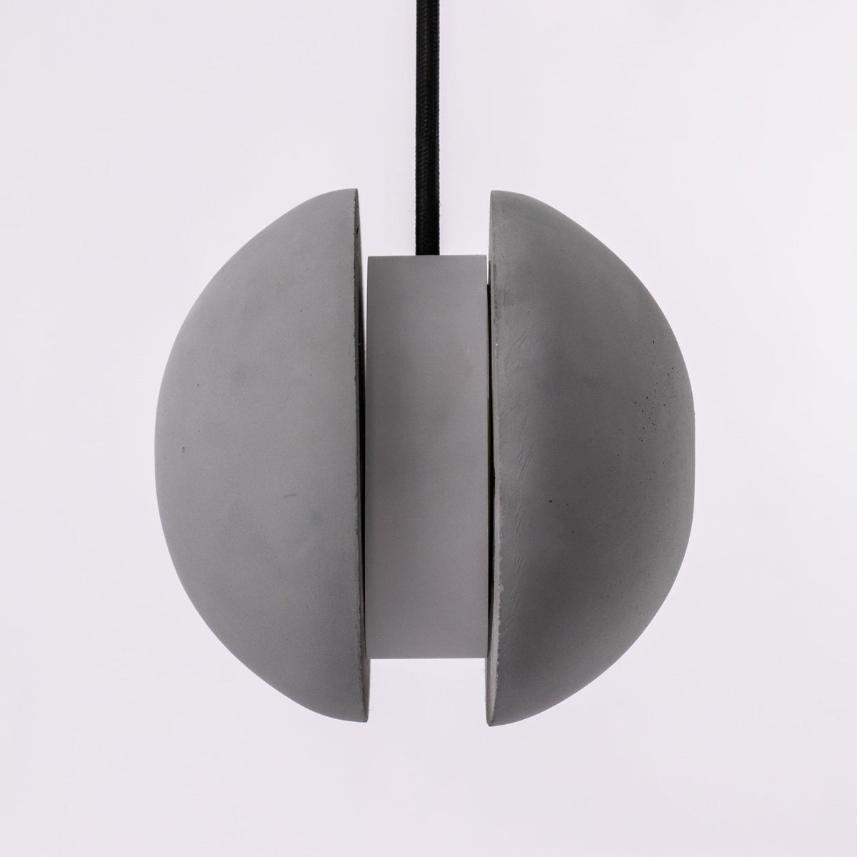 Front view of the split Clérachic concrete pendant, two grey halves parted around a central cylinder.