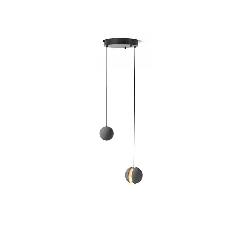 Two Clérachic concrete pendants hang from a small round black canopy on a white backdrop, one with a lit slot.