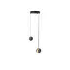 Two Clérachic concrete pendants hang from a small round black canopy on a white backdrop, one with a lit slot.